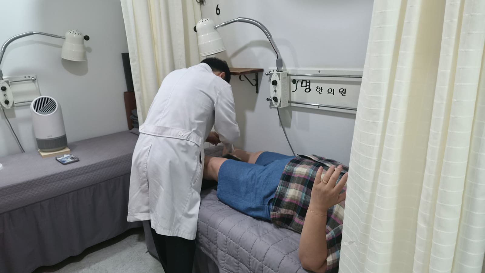 치료 베드에서 원장이 환자 다리에 침을 놓는 모습