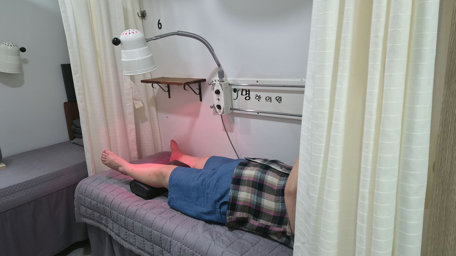 침 치료 중인 다리에 적외선 조사기를 비추는 모습